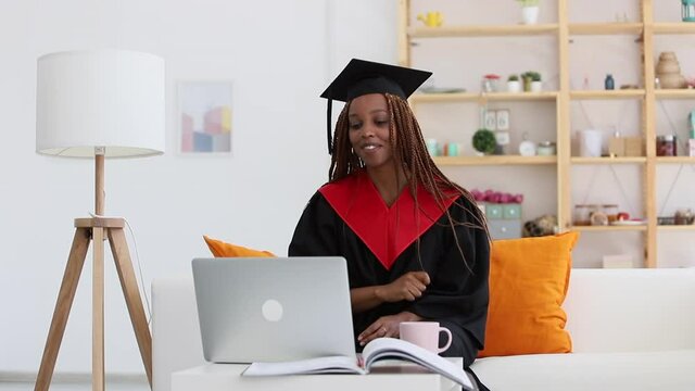 woman in graduation costume gestures and smiles when video calling relatives parents Spbi, telling about achievement and education. happy african american girl distant chatting