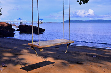 Lonely swing in sulight over sand beach