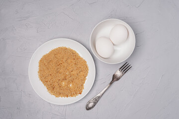 Fresh eggs and bread crumbs on a gray surface. Top view.