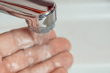 Close-up of a man's hand under a stream of clean water from a tap, copy space