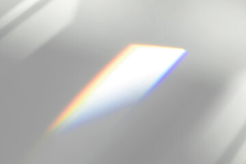 Blurred overlay effect for photo and mockups. Organic drop diagonal shadow and ray of light with rainbow from window on a white wall.