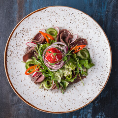Meat salad with roast beef and vegetables on a plate. Top view