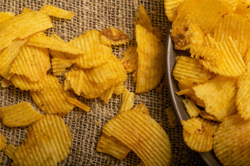 Fluted potato chips on a background of homespun fabric with a rough texture. Close up.