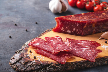 Sliced salami on wooden cutting board.