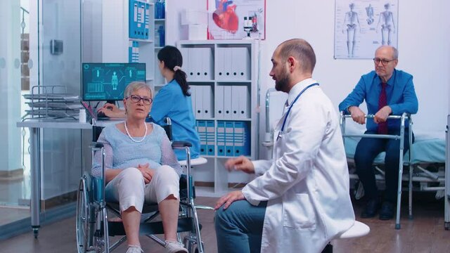 Doctor in recovery clinic using AR to show elderly woman her medical problems while she sitts in a wheelchair. Futuristic medicine with technology and virtual reality. Health care of the future