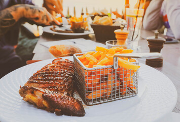 Duck magret breast with fried potato, french cuisine on white plate, people having dinner at restuarant terrace during the sunset