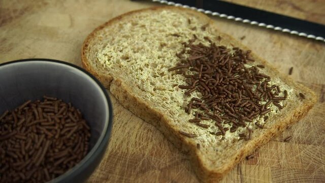 A typical dutch breakfast with a sandwich sprinkled with chocolate sprinkles. Slow motion