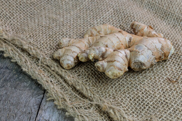 Ingwer-Wurzel auf altem verwitterten Holu und Sackleinen-Stoff / Jute