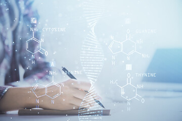 DNA theme hologram over woman's hands writing background. Concept of education. Double exposure
