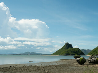 Mountain and green forest on the island and reef boulders on sandy area, Beach with sea smooth and...