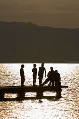 Silhouette of children fishing on a gangway
