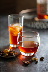 2 glasses of whisky with ice on dark background.  Accessorised with dish of nuts and decorative drinks tray in background