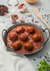 Traditional spicy meatballs in tomato sauce with pepper, garlic and parsley