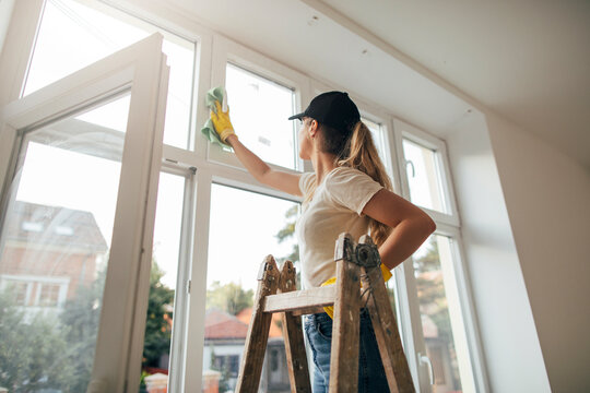 Side view of woman on a ladder cleaning window
