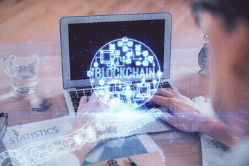 Blockchain theme hologram with man working on computer on background. Concept of crypto chain. Double exposure.