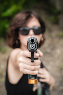 Attractive soldier woman practice shooting and gun point aim to attacker. Close-up pistol pointing front view. Nature outdoor