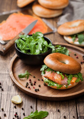 Fresh healthy organic sandwich with bagel and salmon, cream cheese and wild rocket in bowl with bread and smoked salmon pack.