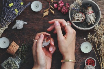 Witches hands on a table ready for spell work. Wiccan witch altar filled with sage smudge sticks,...