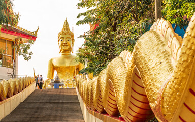 On the top of a big hill in Pattaya, Thailand, lies the Wat Phra Yai temple - or in English: The Big Buddha. At about 60 feet or 18 meters tall this golden Buddha statue sits at the top of the stairs.