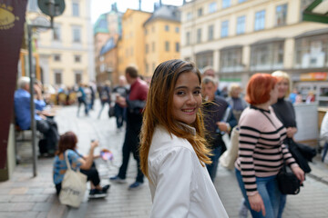 Happy young beautiful Asian tourist woman smiling against view of the public square street at Old Town in Sweden