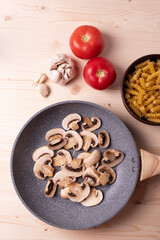 raw champignon mushrooms and tomatoes on the rustic wooden surface