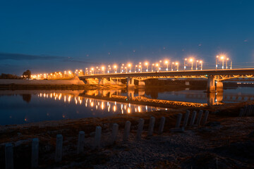 Fototapeta na wymiar bridge with illumination across the river in summer evening