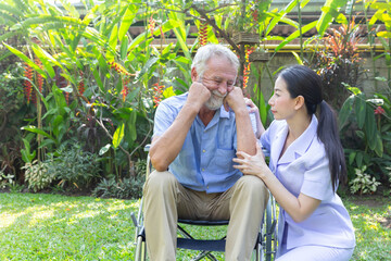 Nurse take care a depressed thoughtful senior retirement man on his wheelchair in a garden in his home