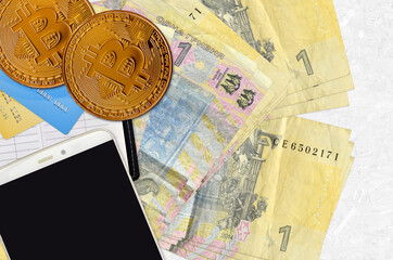 1 Ukrainian hryvnia bills and golden bitcoins with smartphone and credit cards. Cryptocurrency investment concept. Crypto mining or trading