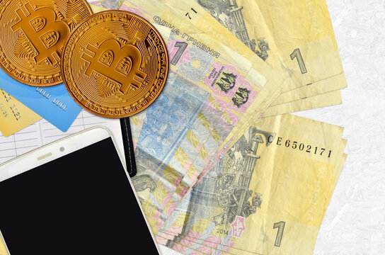 1 Ukrainian hryvnia bills and golden bitcoins with smartphone and credit cards. Cryptocurrency investment concept. Crypto mining or trading