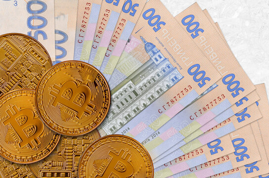 500 Ukrainian hryvnias bills and golden bitcoins. Cryptocurrency investment concept. Crypto mining or trading