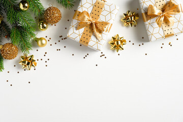 Christmas flat lay composition. Top view gold pine tree branch, Xmas decorations, golden balls and gift boxes on white background. Christmas, winter, New Year concept.