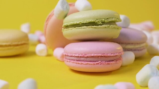 Marshmallow falls on macarone yellow background bakery food color sugar pearl french dessert delicious table macaroon slow motion
