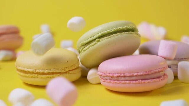 On yellow background marshmallow falls on macarone bakery food color sugar pearl french dessert delicious table macaroon slow motion