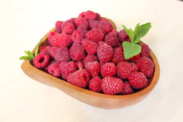 Large raspberries are decorated with a mint leaf on a white background