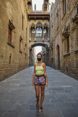 Fototapeta na wymiar Woman wearing a surgical mask, walking the empty streets of Barcelona during the coronavirus.