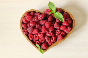 Sweet ripe raspberries are decorated with a mint leaf on a white background