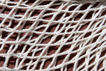 Fototapeta na wymiar beige mesh zero waste bag close up texture on a brown background