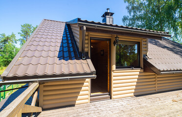 Large wooden terrace on the second floor in private country house near the forest. Sunny summer day. Entrance door.