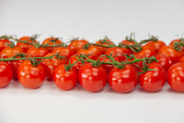 Fresh cherry tomatoes on branch on white background.
