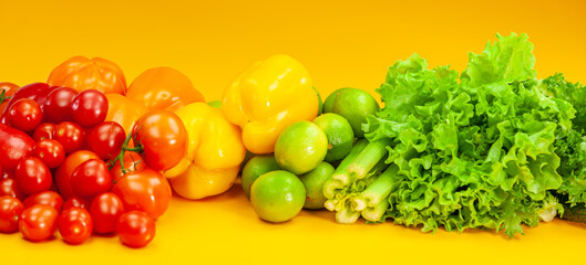 A set of vegetables lies on a yellow background. Tomatoes, peppers, limes and celery.