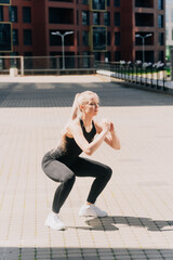 A girl in sportswear outdoors does squats, exercise of the gluteal muscles for weight loss