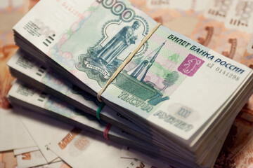 A bundle of banknotes on the background of other banknotes. 1000 and 5000 rubles