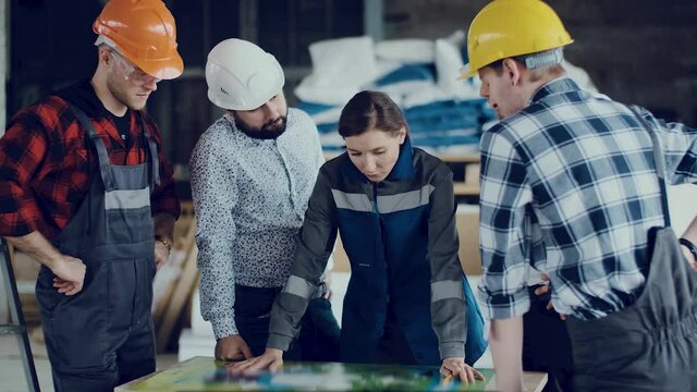 Teamwork of construction engineers studying the plan of an object at a construction site.