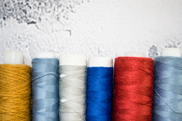 Multicolored spools of thread on light marble background. Free space for text. Wallpaper