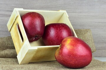 Close up red apple, background two units in small wooden box on a light cloth