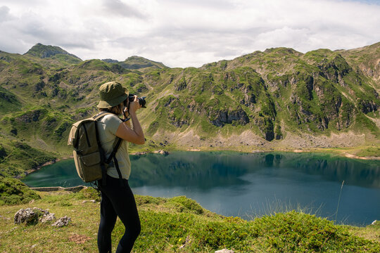 Young woman taking a picture of a lake with her digital camera in Somiedo Natural Park, Asturias.
