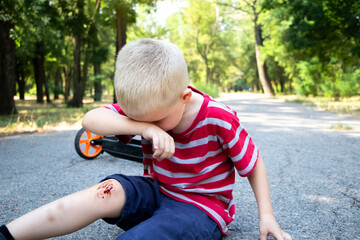 A four-year-old boy fell off a scooter and broke his knee. Dad provides first aid by disinfecting...