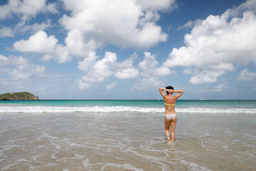 Brunette Caucasian woman in swimsuit standing in beautiful and clear water on the beach in Mexico , Caribbean Sea