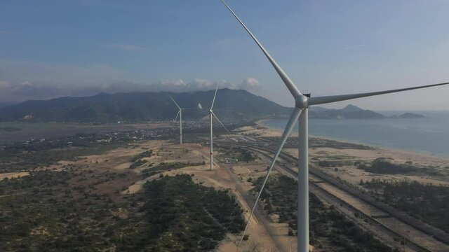 Aerial view of windmills farm for energy production on beautiful cloudy sky at beach. Wind power turbines generating clean renewable energy for sustainable development, Quy Nhon, Binh Dinh, Vietnam