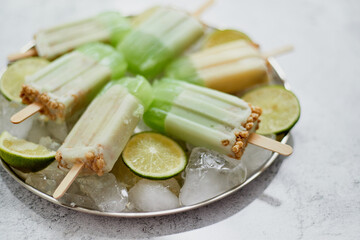 Summer refreshing homemade lime popsicles with chipped ice over stone background
